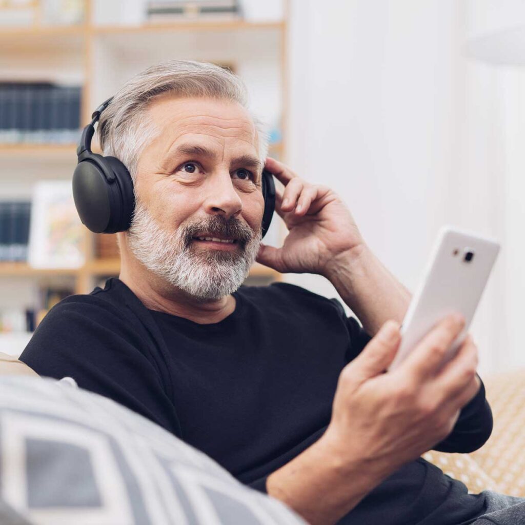 Middle-aged man listening to music online at home Man Learning More